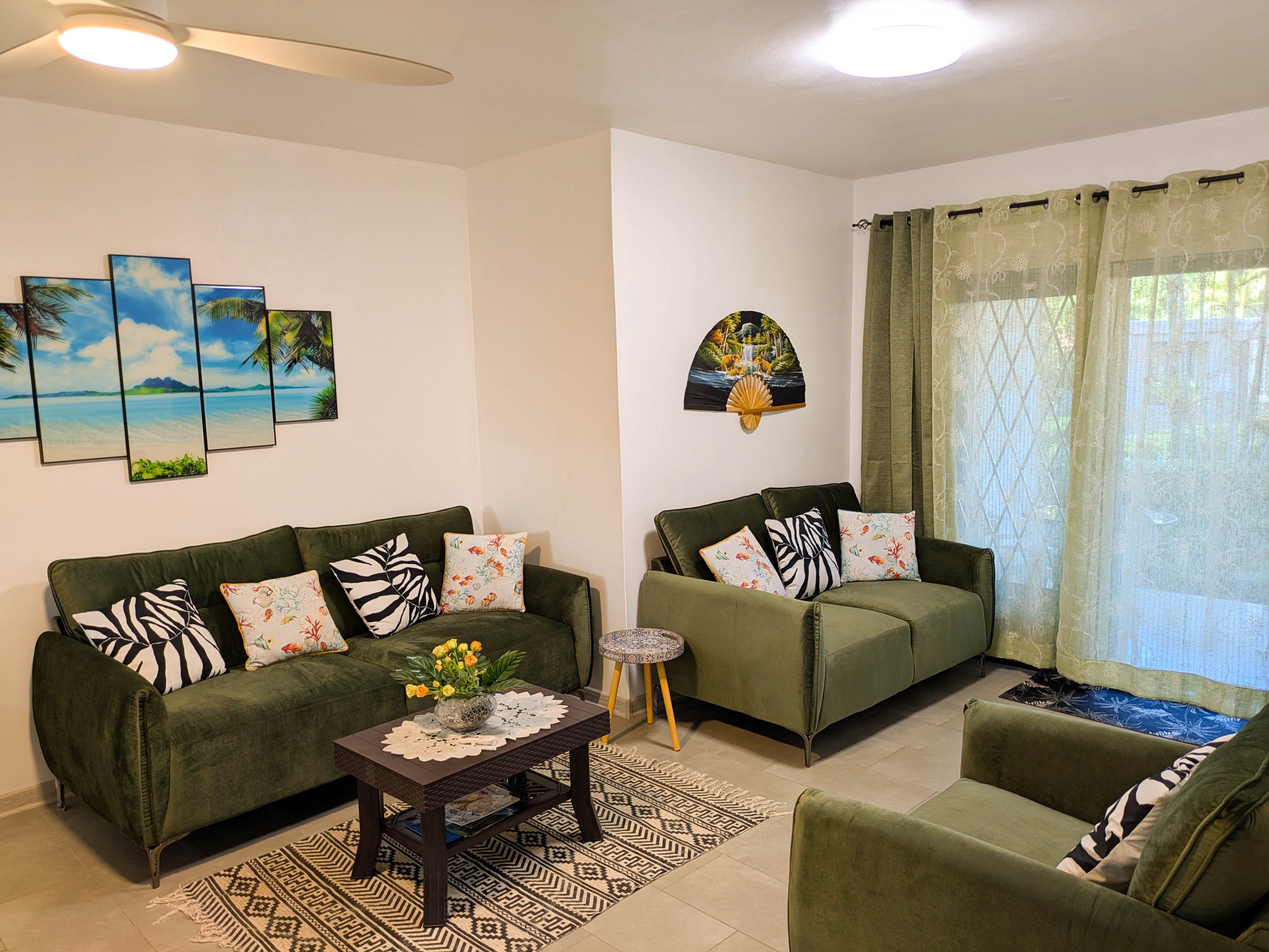 Living room of Coconut Palm Retreat — green sofas with tropical wall art